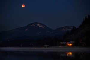 Orange moon over cabin and mountain