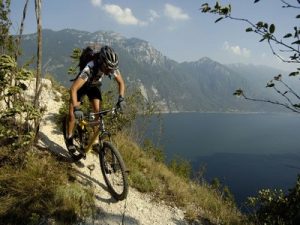 person mountain biking in front of lake and mountains