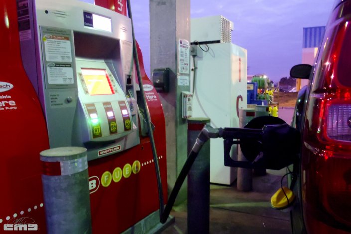 a gas pump fueling up a red car.